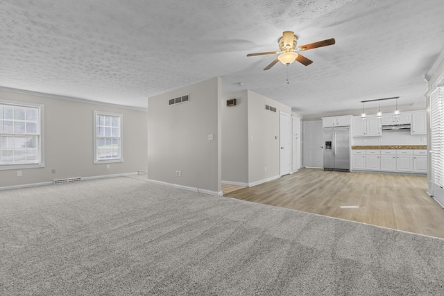 unfurnished living room featuring ceiling fan, light carpet, and a textured ceiling