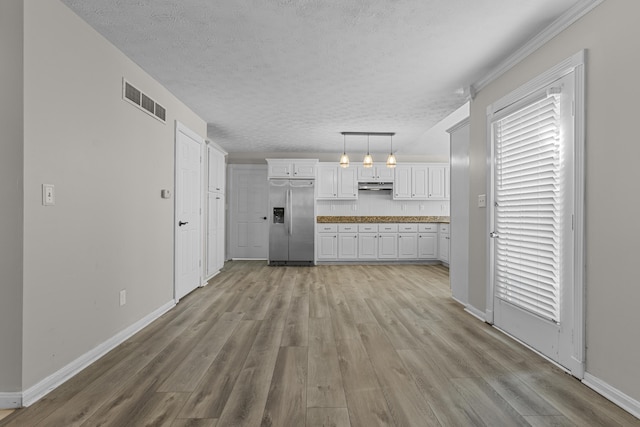 kitchen with decorative light fixtures, light hardwood / wood-style floors, white cabinetry, a textured ceiling, and stainless steel fridge