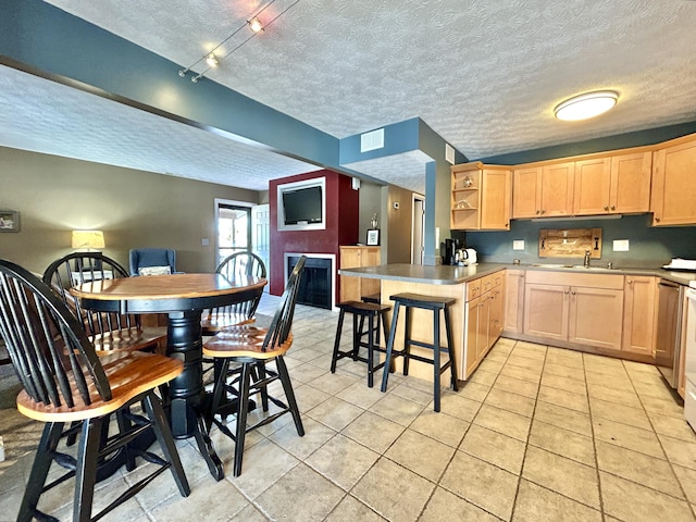 kitchen featuring kitchen peninsula, light brown cabinets, a kitchen breakfast bar, track lighting, and a textured ceiling