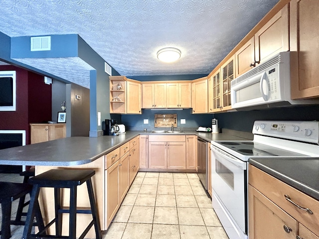 kitchen featuring white appliances, a kitchen bar, light brown cabinets, kitchen peninsula, and light tile patterned flooring