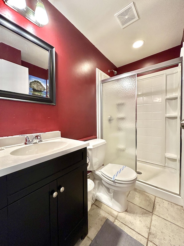 bathroom with a shower with shower door, toilet, and vanity