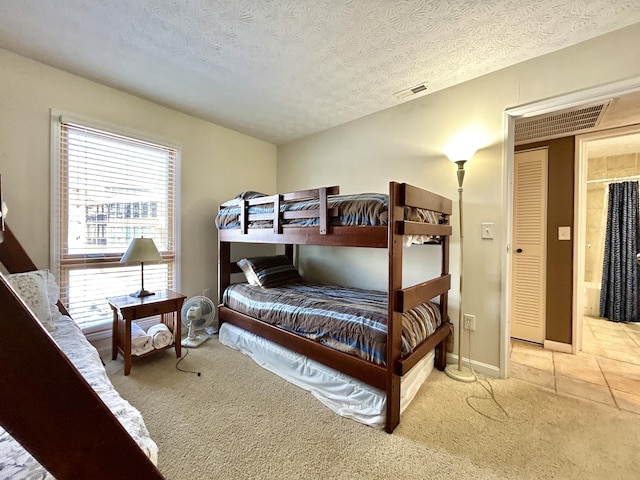 bedroom featuring light carpet, a textured ceiling, and multiple windows