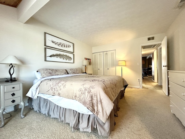 bedroom featuring light carpet, a closet, and a textured ceiling