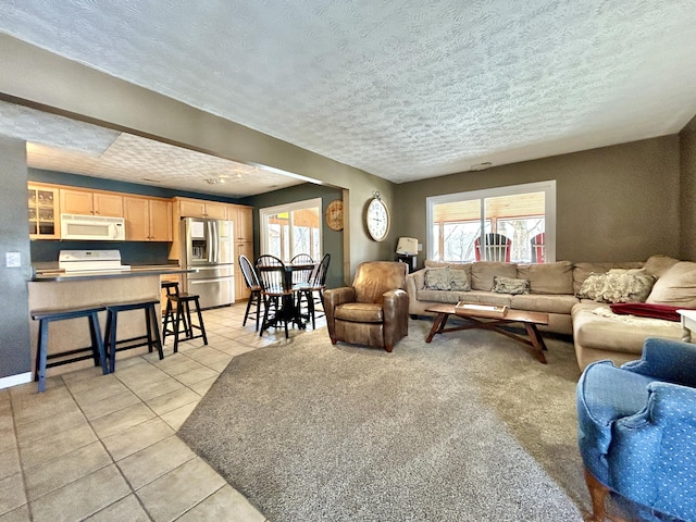 living room with a textured ceiling, light tile patterned floors, and a healthy amount of sunlight