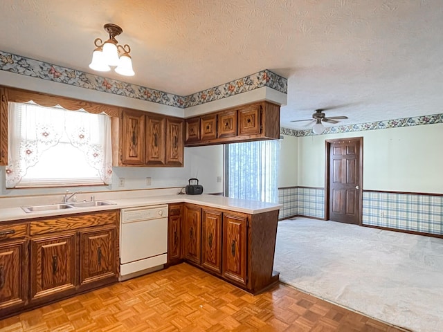 kitchen with kitchen peninsula, white dishwasher, sink, a textured ceiling, and light parquet flooring