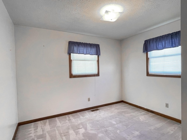 unfurnished room featuring light carpet, plenty of natural light, and a textured ceiling