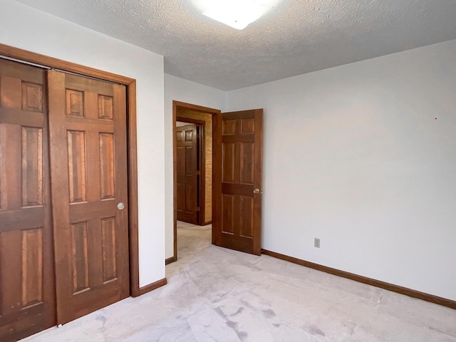 unfurnished bedroom featuring a closet, a textured ceiling, and light carpet