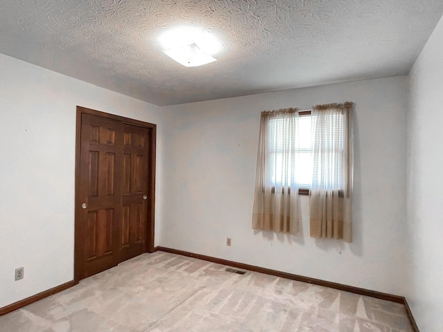 empty room featuring a textured ceiling and light carpet