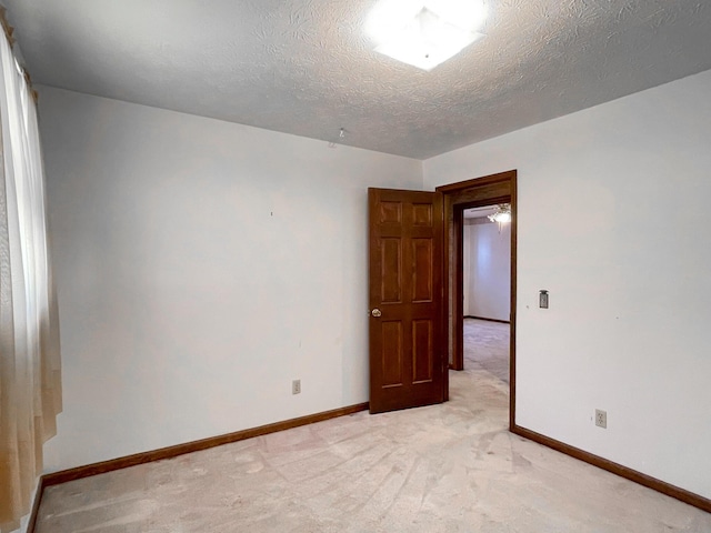 spare room featuring a textured ceiling and light carpet