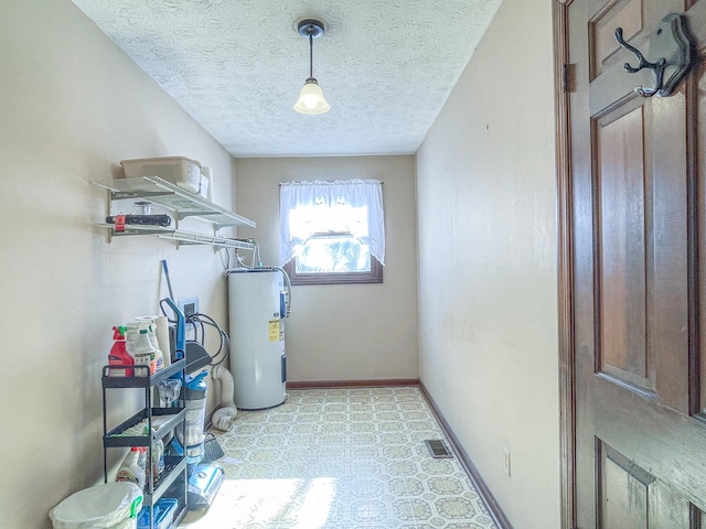 clothes washing area with a textured ceiling and electric water heater