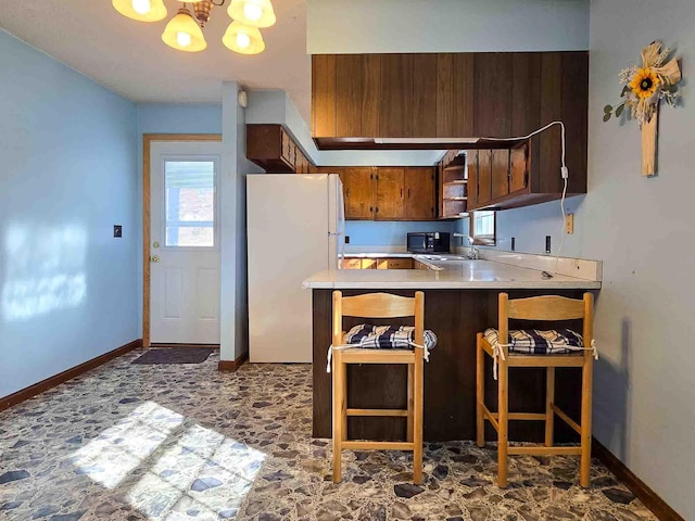 kitchen with a kitchen bar, a chandelier, white fridge, sink, and kitchen peninsula