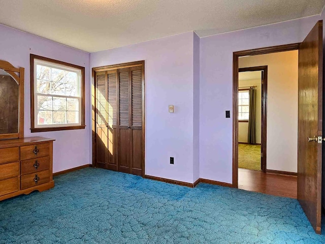 unfurnished bedroom with a textured ceiling, a closet, and dark carpet