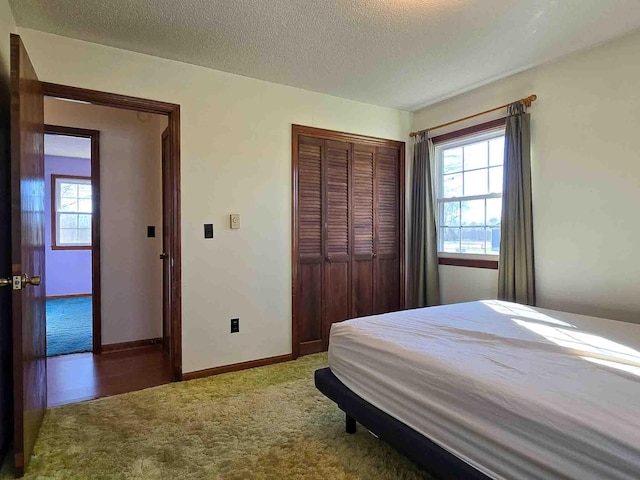 carpeted bedroom featuring a textured ceiling and a closet