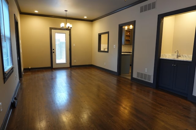 foyer featuring sink, crown molding, dark wood-type flooring, and a chandelier