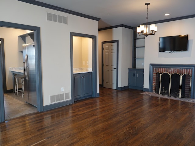 unfurnished living room featuring a notable chandelier, crown molding, a fireplace, and dark hardwood / wood-style floors