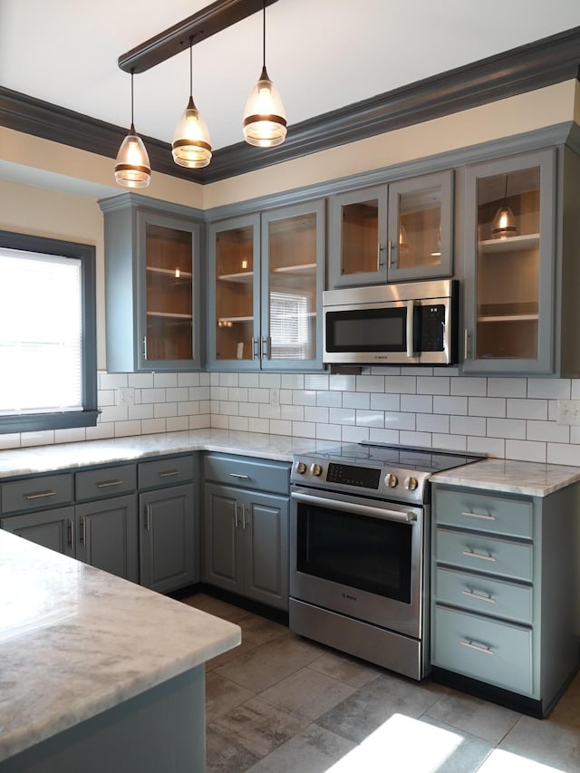 kitchen featuring gray cabinetry, appliances with stainless steel finishes, pendant lighting, light stone countertops, and backsplash