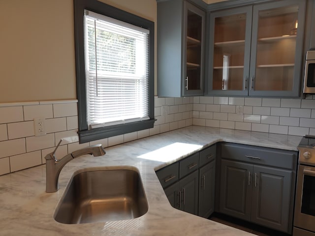 kitchen featuring light stone counters, sink, gray cabinets, and stainless steel appliances