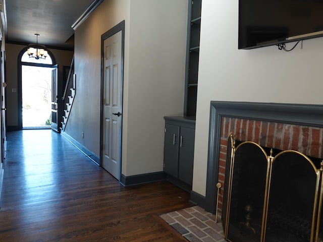 entryway with dark hardwood / wood-style flooring, ornamental molding, and a chandelier