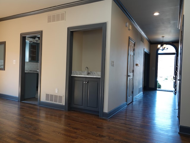 hallway with crown molding, sink, a notable chandelier, and dark hardwood / wood-style flooring