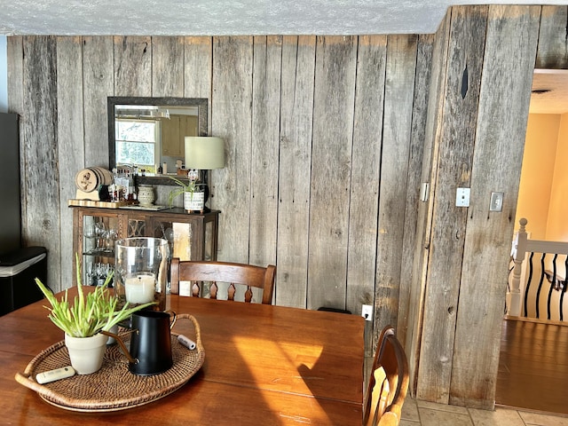 tiled dining room featuring a textured ceiling and wooden walls