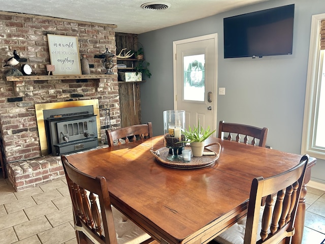 dining space featuring a brick fireplace, light tile patterned floors, and a textured ceiling