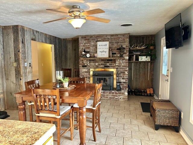 tiled dining room featuring a fireplace, wood walls, and a textured ceiling