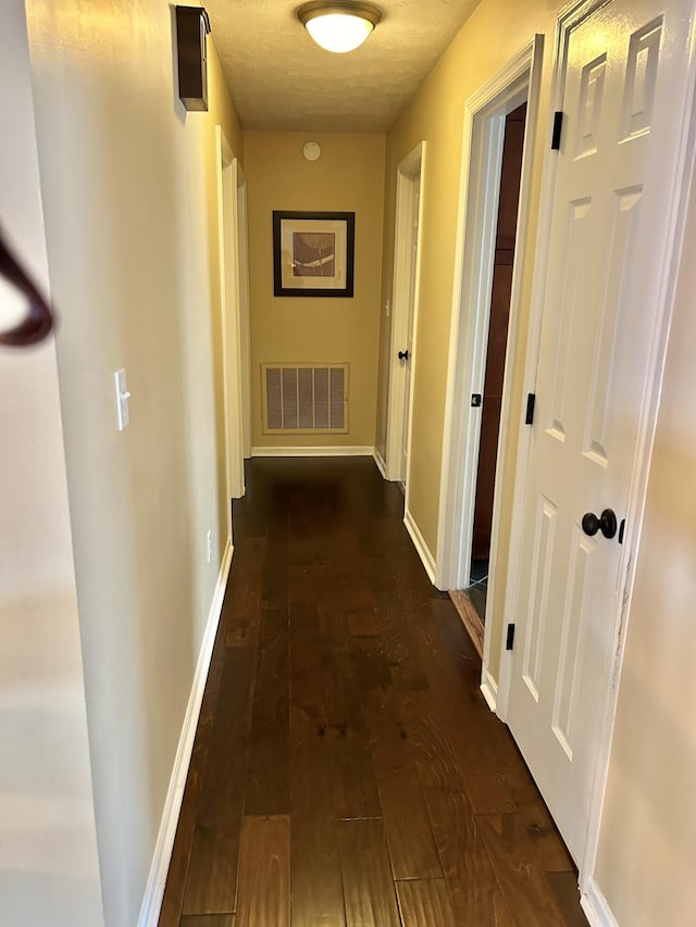 hallway featuring a textured ceiling and dark hardwood / wood-style flooring