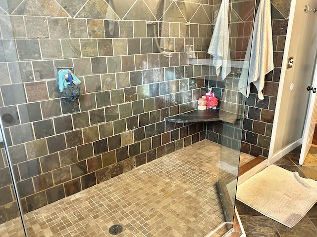 bathroom with a tile shower and tile patterned floors