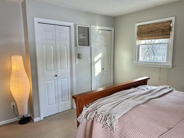 bedroom featuring light colored carpet and two closets