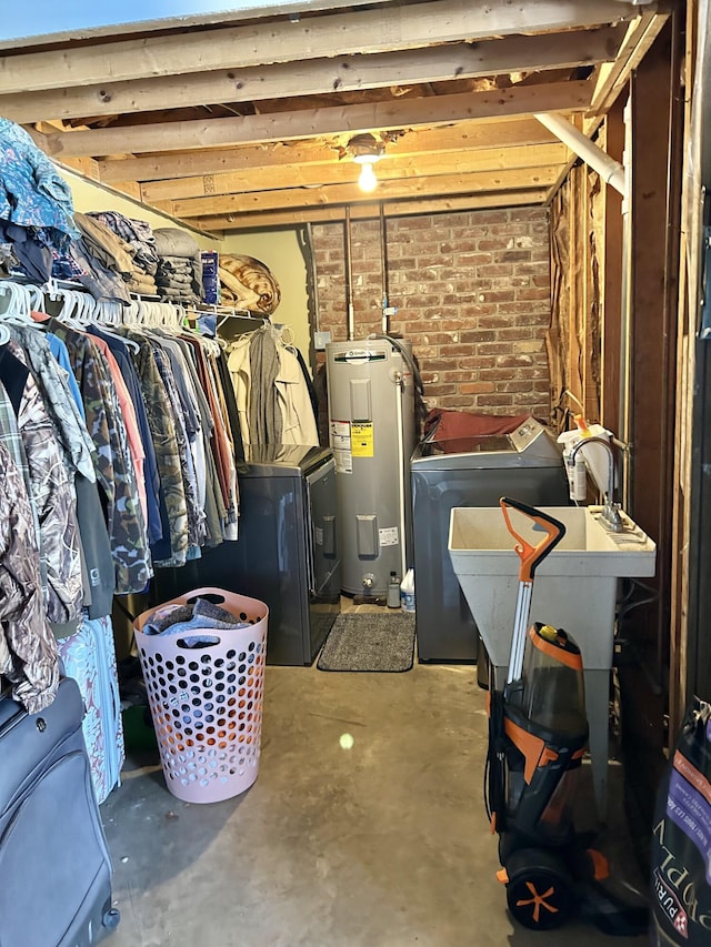 basement with independent washer and dryer, brick wall, and electric water heater