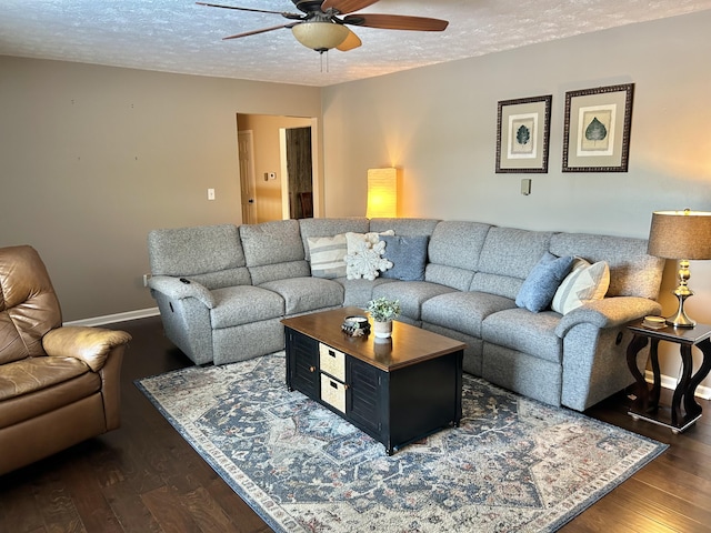 living room featuring ceiling fan, dark wood-type flooring, and a textured ceiling