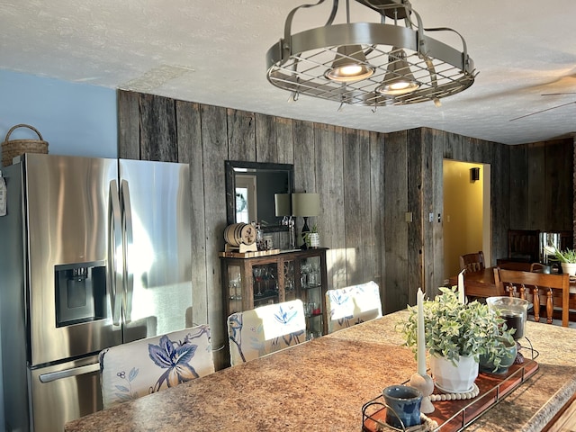 dining space featuring a textured ceiling and wooden walls