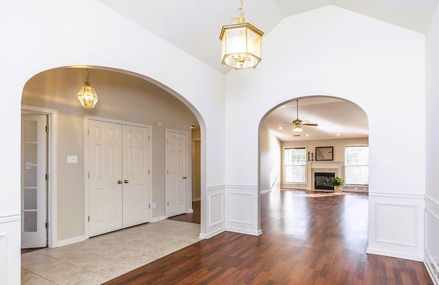 entrance foyer featuring ceiling fan with notable chandelier, wood-type flooring, and high vaulted ceiling