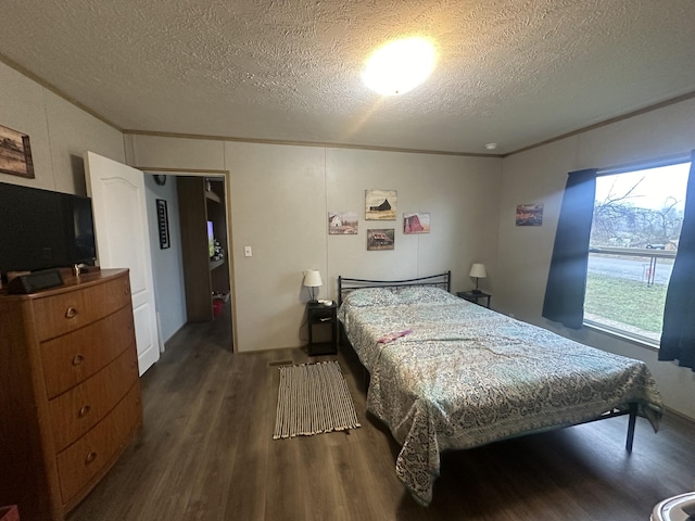 bedroom with a textured ceiling, dark wood-type flooring, and ornamental molding