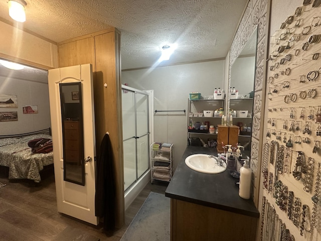 bathroom with vanity, a shower with door, a textured ceiling, and hardwood / wood-style flooring