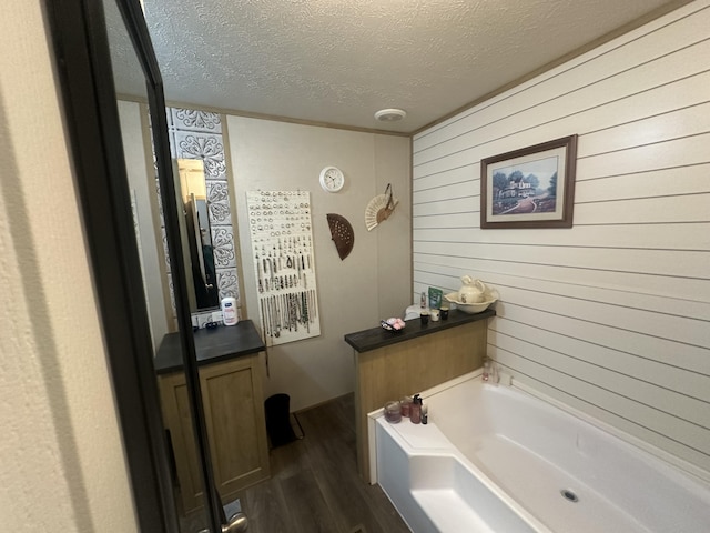 bathroom with a washtub, a textured ceiling, hardwood / wood-style floors, and wooden walls