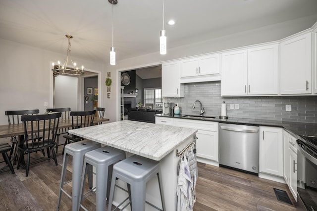 kitchen with stainless steel appliances, sink, white cabinets, and decorative light fixtures