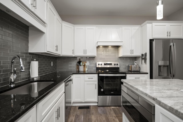 kitchen with white cabinets, stainless steel appliances, sink, and dark stone counters