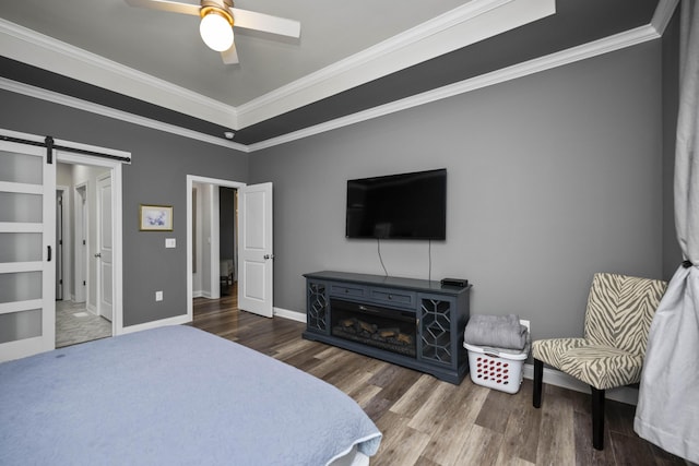 bedroom with wood-type flooring, a barn door, and crown molding