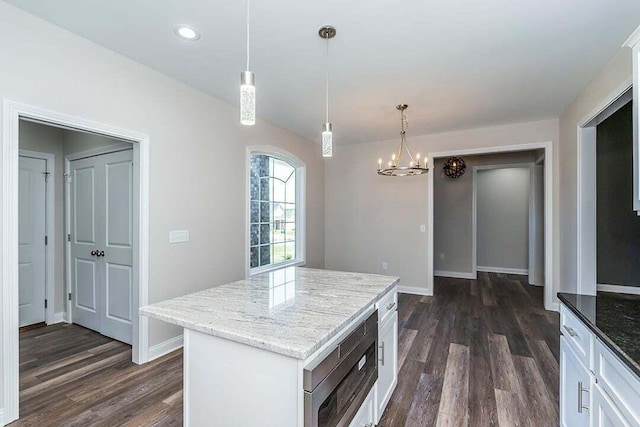 kitchen featuring a kitchen island, stainless steel microwave, decorative light fixtures, white cabinets, and dark wood-type flooring