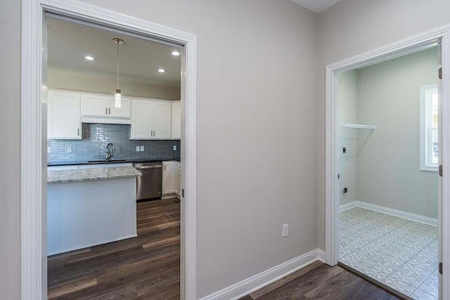 kitchen featuring sink, dishwasher, white cabinetry, hanging light fixtures, and dark hardwood / wood-style flooring