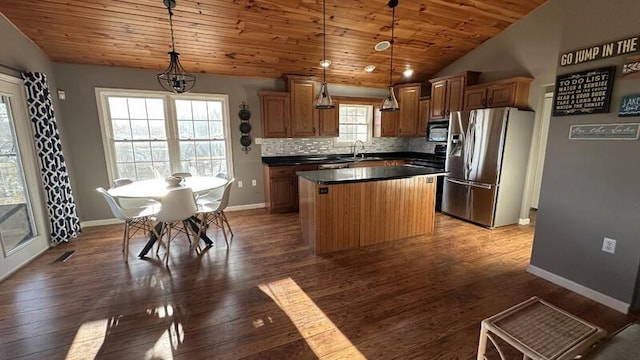 kitchen featuring stainless steel refrigerator with ice dispenser, a center island, sink, and hanging light fixtures