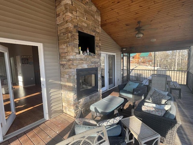 sunroom with lofted ceiling, ceiling fan, wood ceiling, and an outdoor stone fireplace