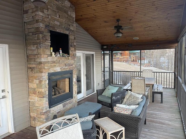 wooden deck with ceiling fan and an outdoor stone fireplace