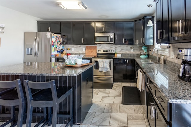 kitchen featuring sink, dark stone countertops, hanging light fixtures, stainless steel appliances, and a center island