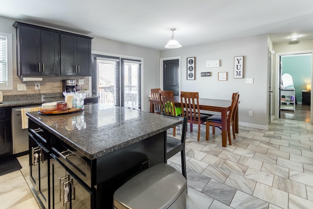 kitchen featuring a kitchen island, backsplash, dark stone counters, hanging light fixtures, and stainless steel dishwasher