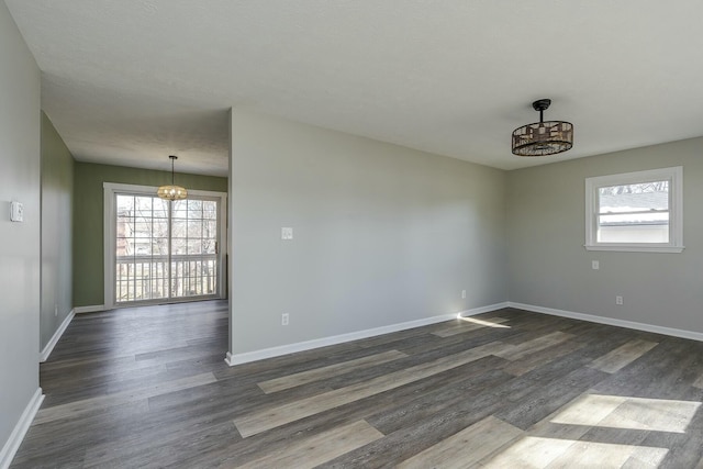 unfurnished room featuring dark hardwood / wood-style flooring and an inviting chandelier