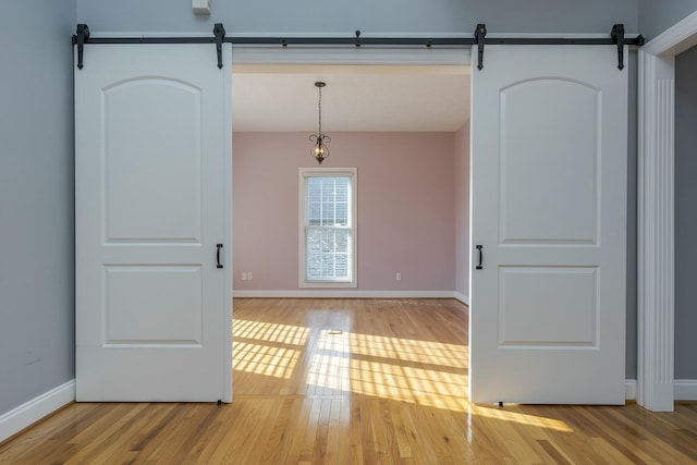 unfurnished room with light wood-type flooring and a barn door