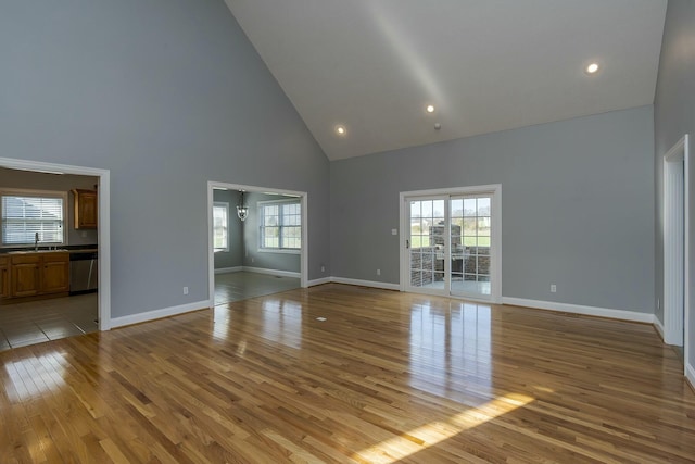 unfurnished living room with high vaulted ceiling and light hardwood / wood-style floors