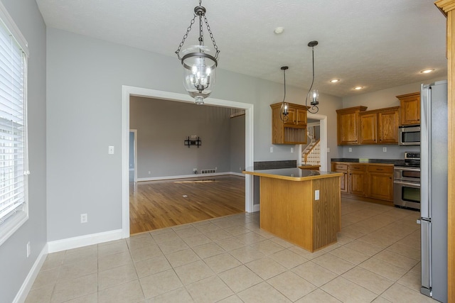 kitchen with pendant lighting, a kitchen island, stainless steel appliances, light tile patterned floors, and a breakfast bar area